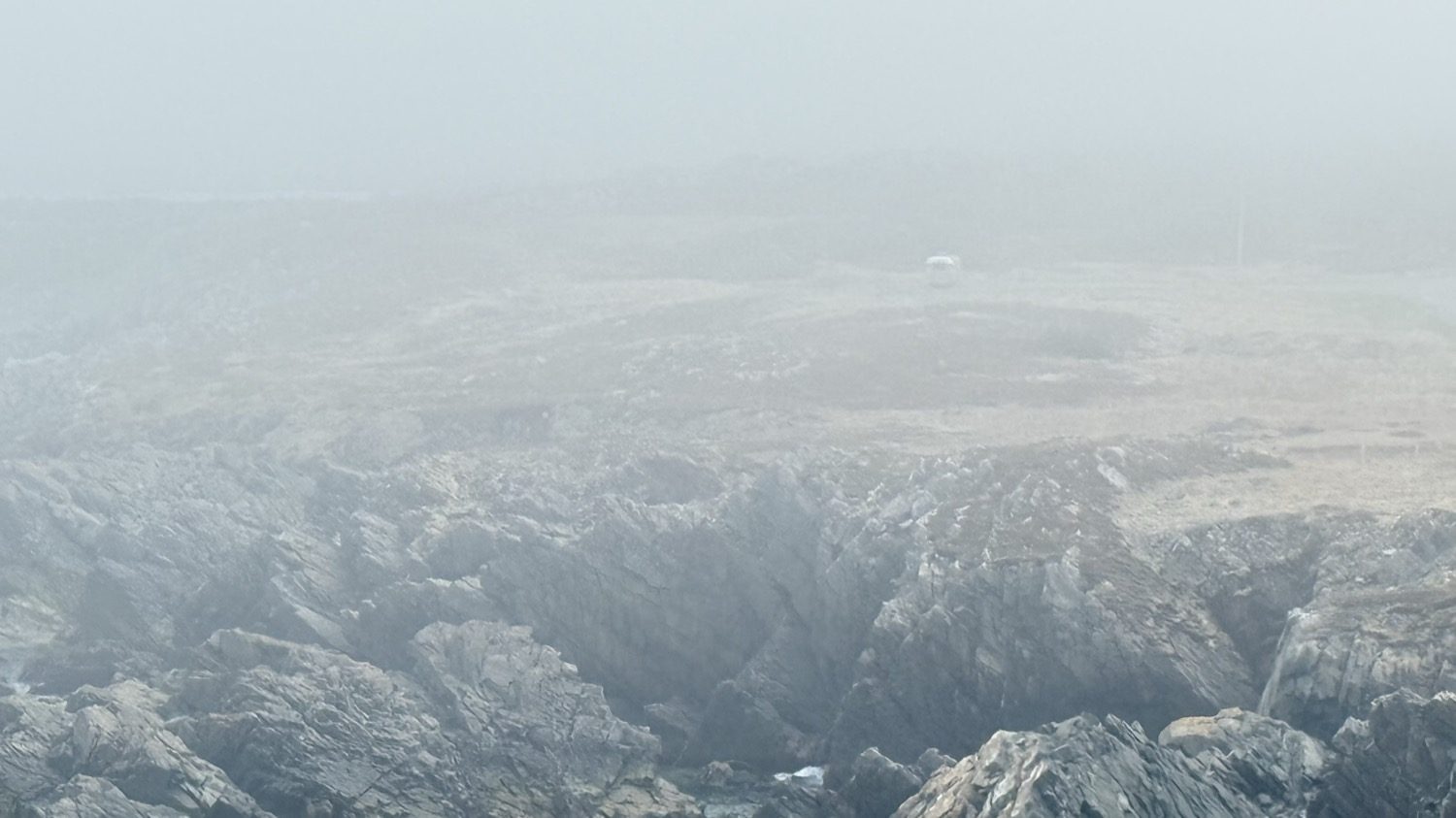 Foggy, treacherous-looking rocky coastline near our campsite, with the Airstream barely visible in the distance