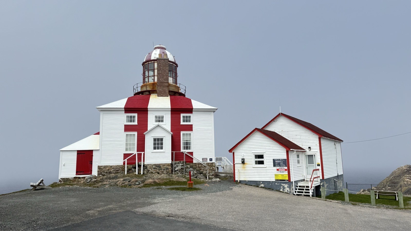 The red and white Cape Bonavista Lighthouse building with its glass lantern room, and the adjoining keeper's outbuilding
