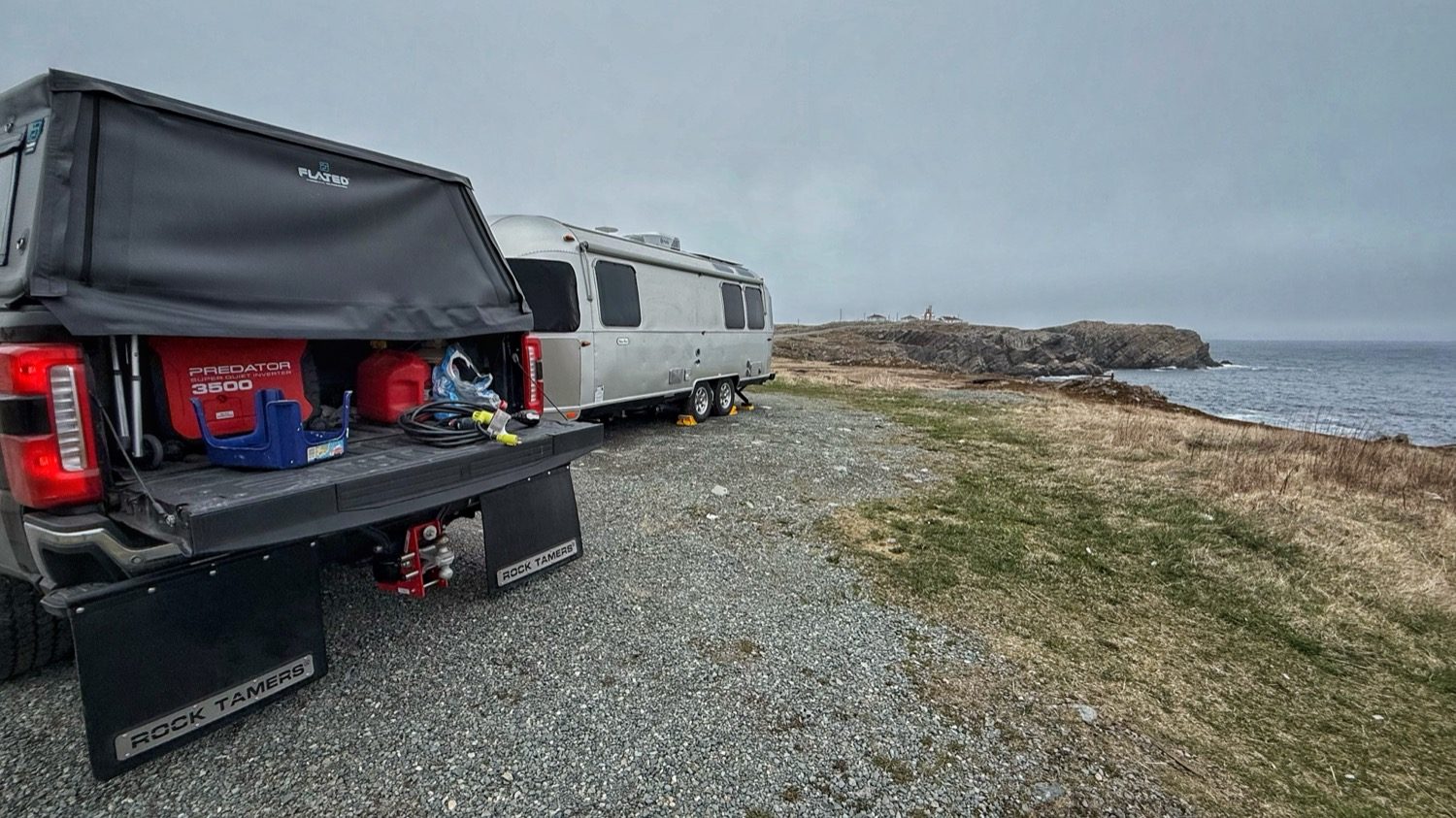 Our truck and Airstream parked on a flat gravel pull-off, with the Bonavista lighthouse visible on the point across the water