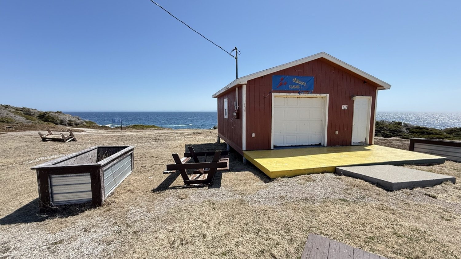 A red day-use building with a yellow ramp at Boutte du Cap Park, overlooking the ocean