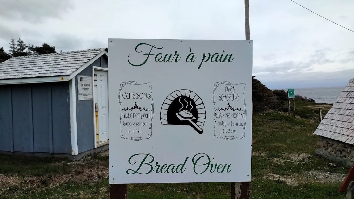 A sign beside the bread oven reading Four a Pain, Bread Oven, with the baking schedule for July and August