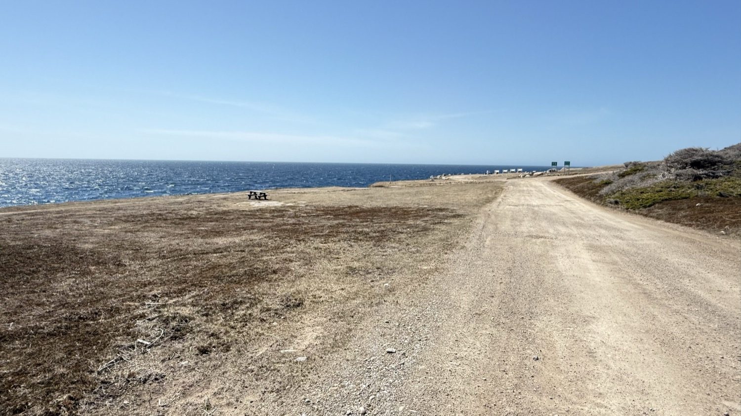 The gravel road running out to the point at Boutte du Cap Park, with a lone picnic table overlooking the ocean