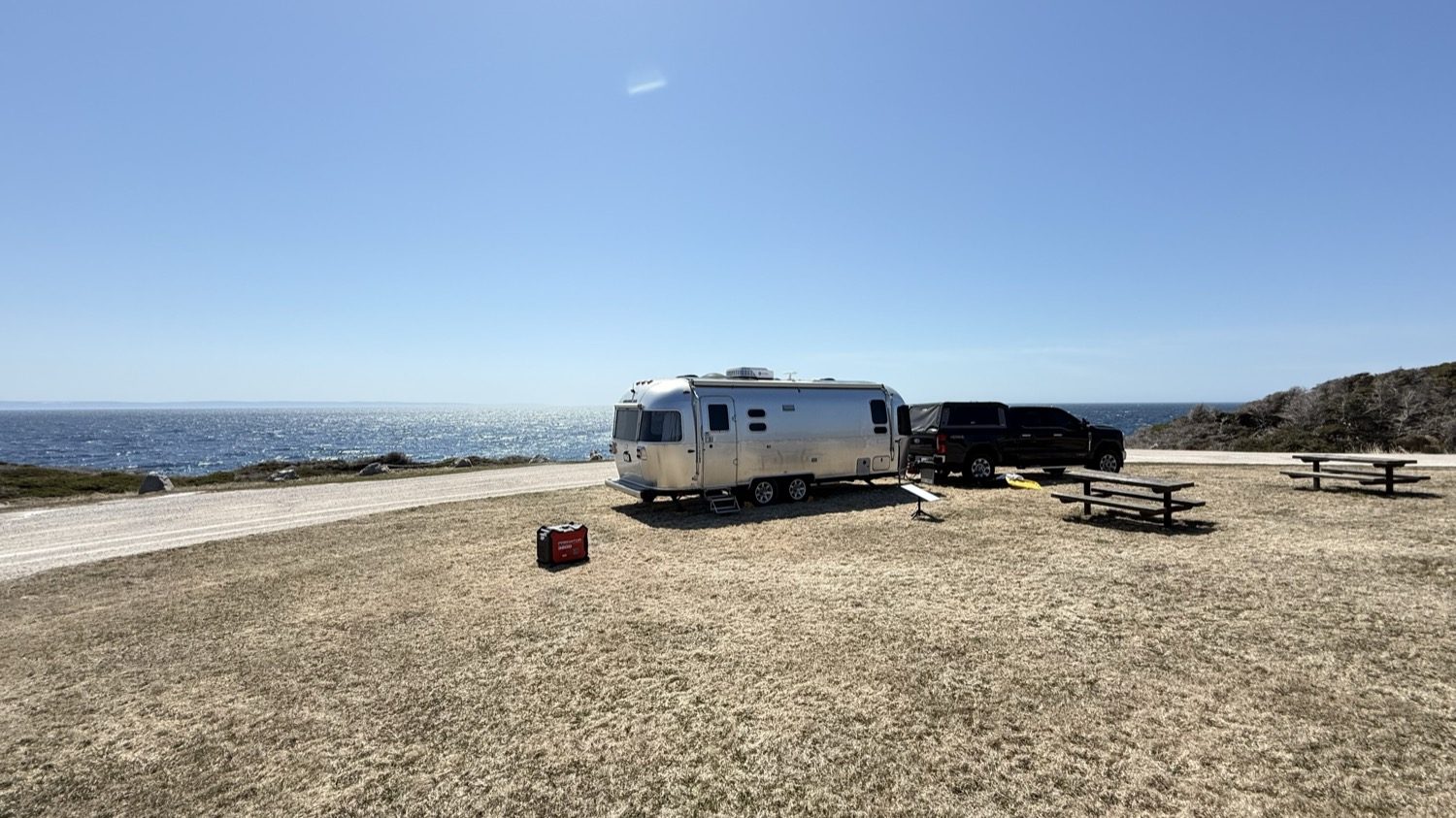 Our truck and Airstream parked on the grass circle at Boutte du Cap Park, with picnic tables and the ocean just beyond