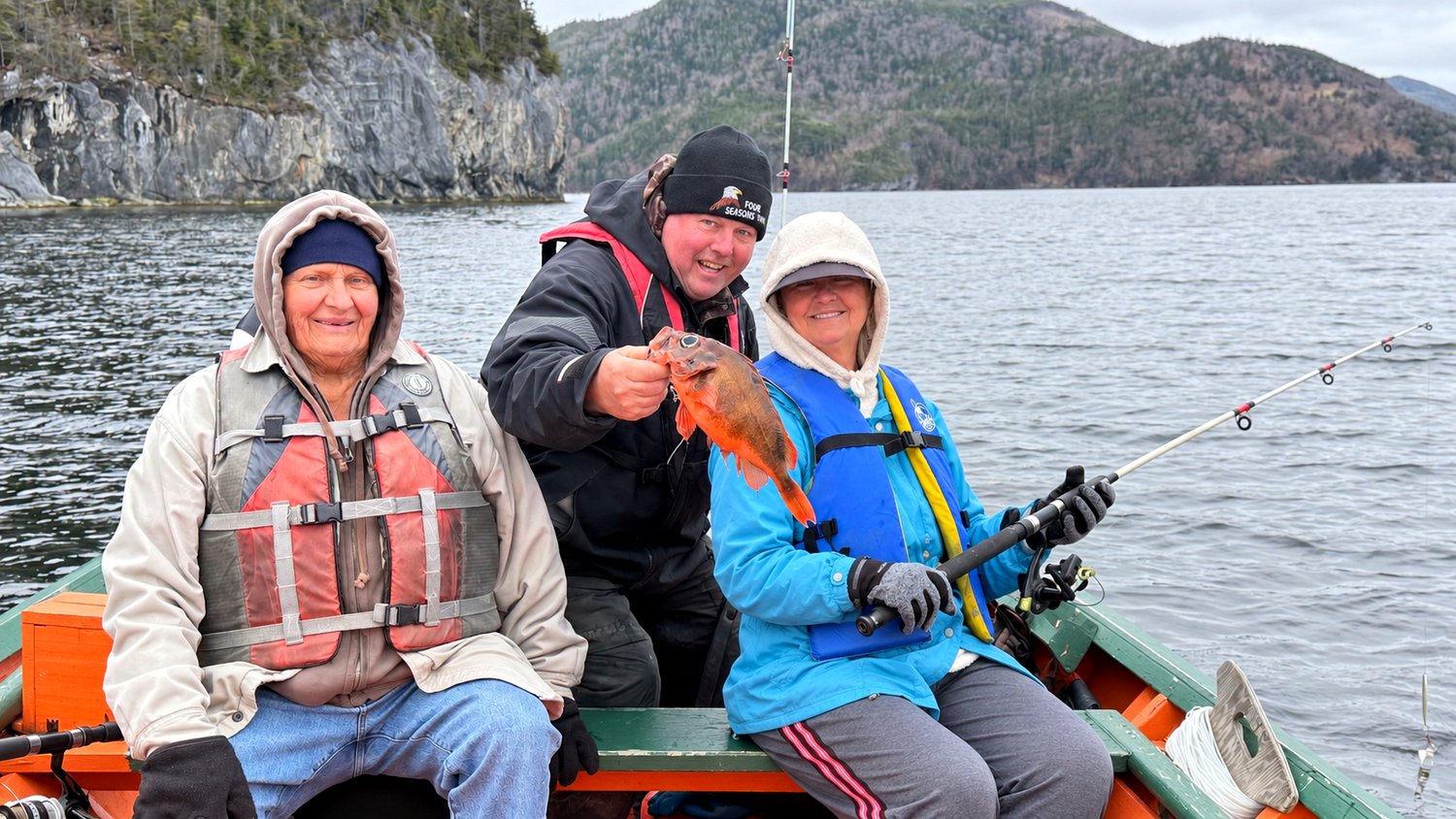 Darren holding up the ocean perch we caught, with Heather's dad and Heather in the boat