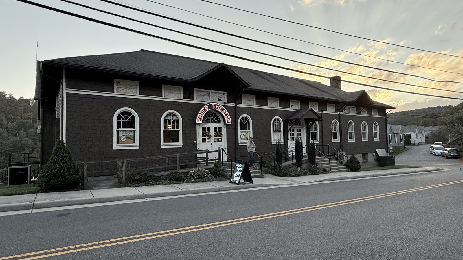 The brown-shingled Historic Fries Theatre at dusk, its red neon sign lit above the front doors