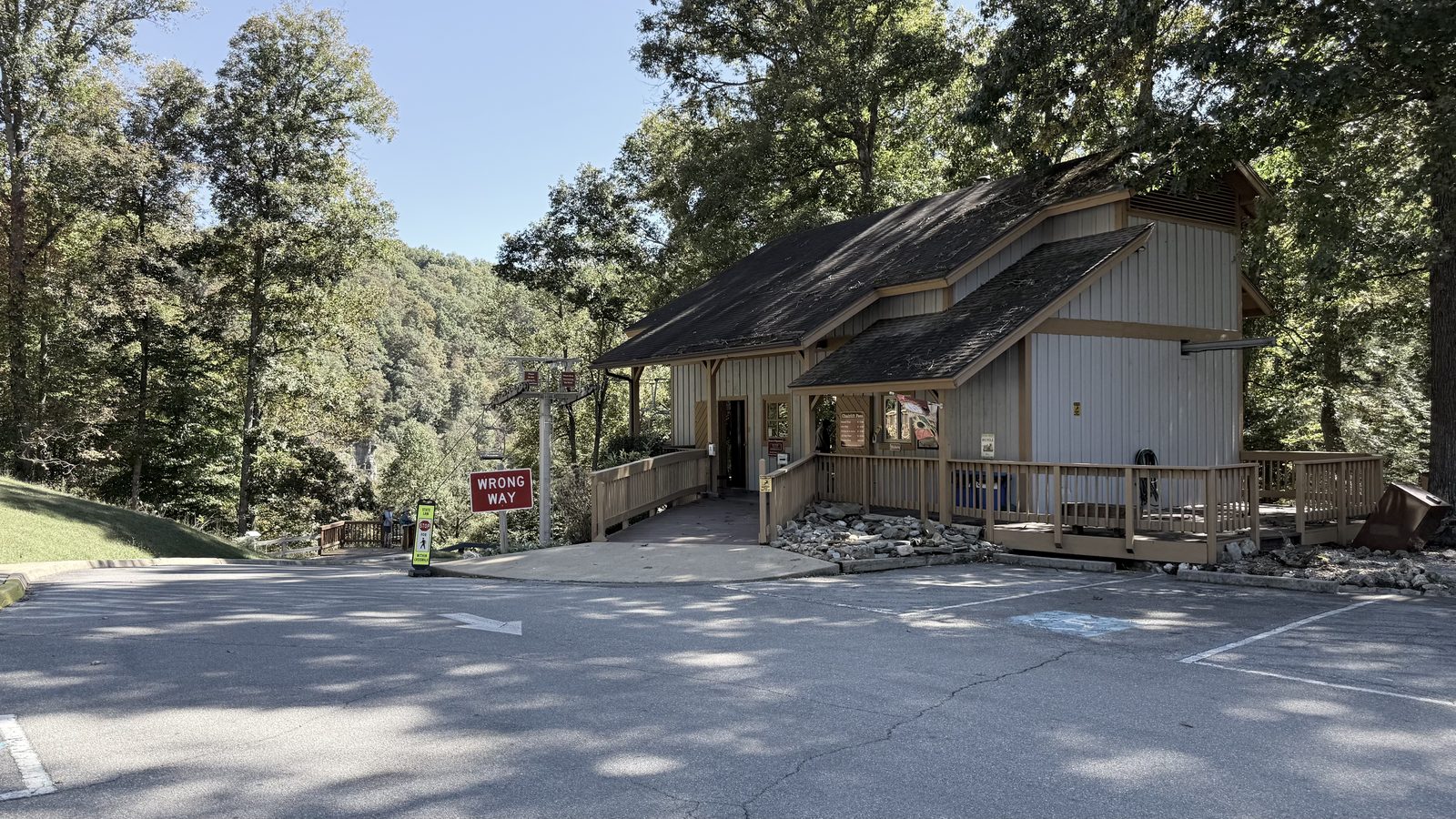 The wood-sided chairlift station at Natural Tunnel State Park, with a covered deck, a parking lot in front and wooded hills behind
