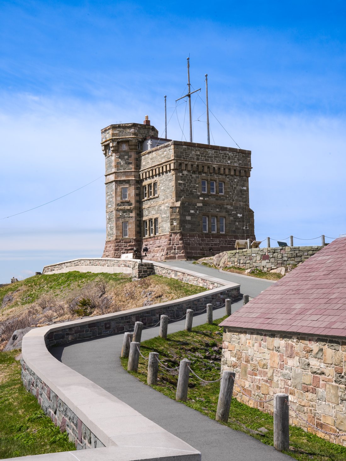 Cabot Tower on Signal Hill, a stone building with a corner turret and two radio masts, reached by a curving paved path