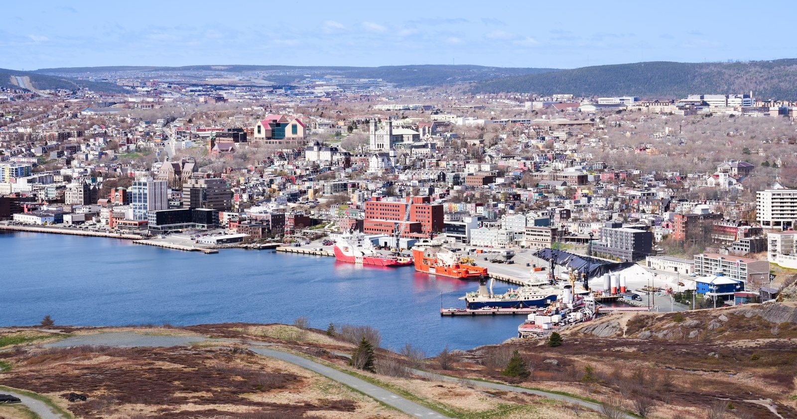 Downtown St. John's from Signal Hill, with red and orange ships docked along the harbor and a stone cathedral among the buildings