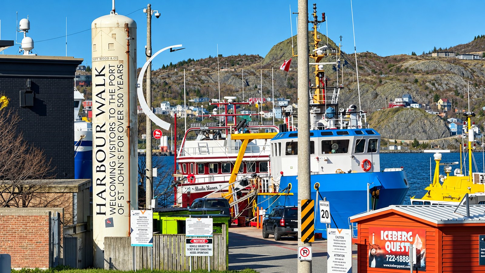 A tall Harbour Walk sign reading Welcoming visitors to the port of St. John's for over 500 years, with boats tied up behind it