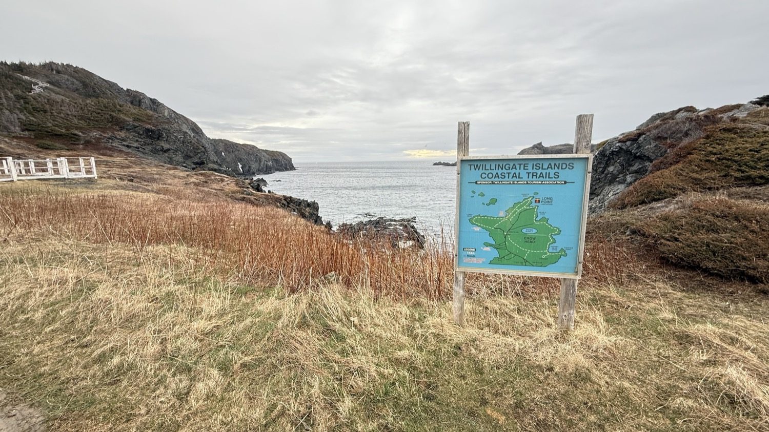The Twillingate Islands Coastal Trails map on a wooden sign beside the ocean