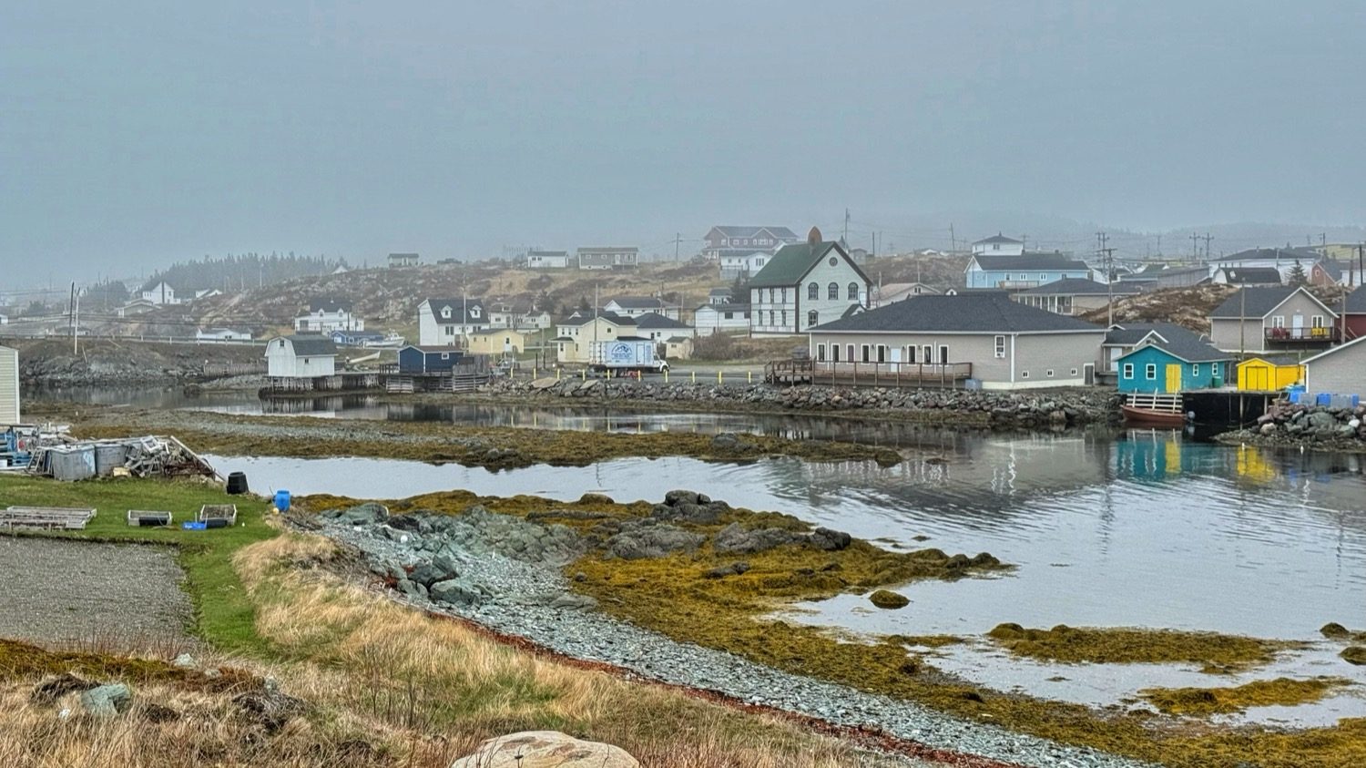 Houses and small colorful buildings along the edge of a tidal cove in Back Harbour