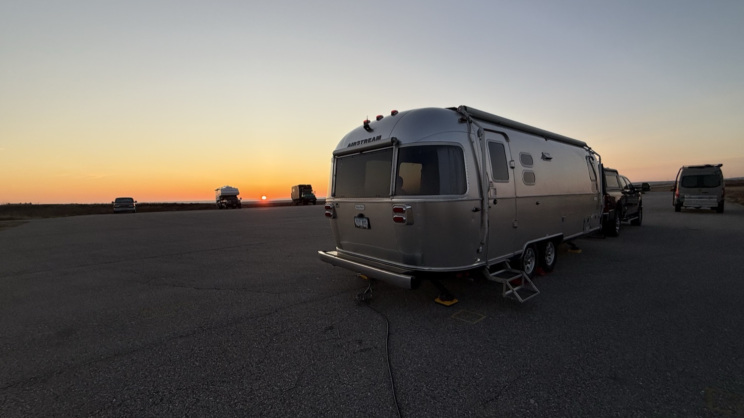 Our Airstream parked in the Wreckhouse lot at sunset, other vehicles visible nearby